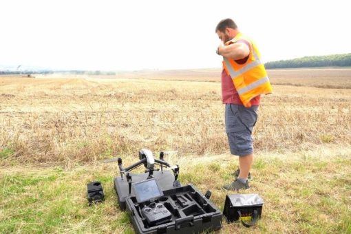 A CAA approved, RUAS trained pilot adjusting his high vis vest and setting up his drone.